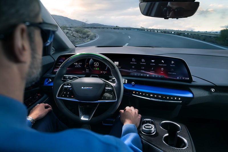 Front View of the 2026 OPTIQ-V Driving Through the Dusk Utilizing its Headlights | Gerry Lane Cadillac in Baton Rouge LA