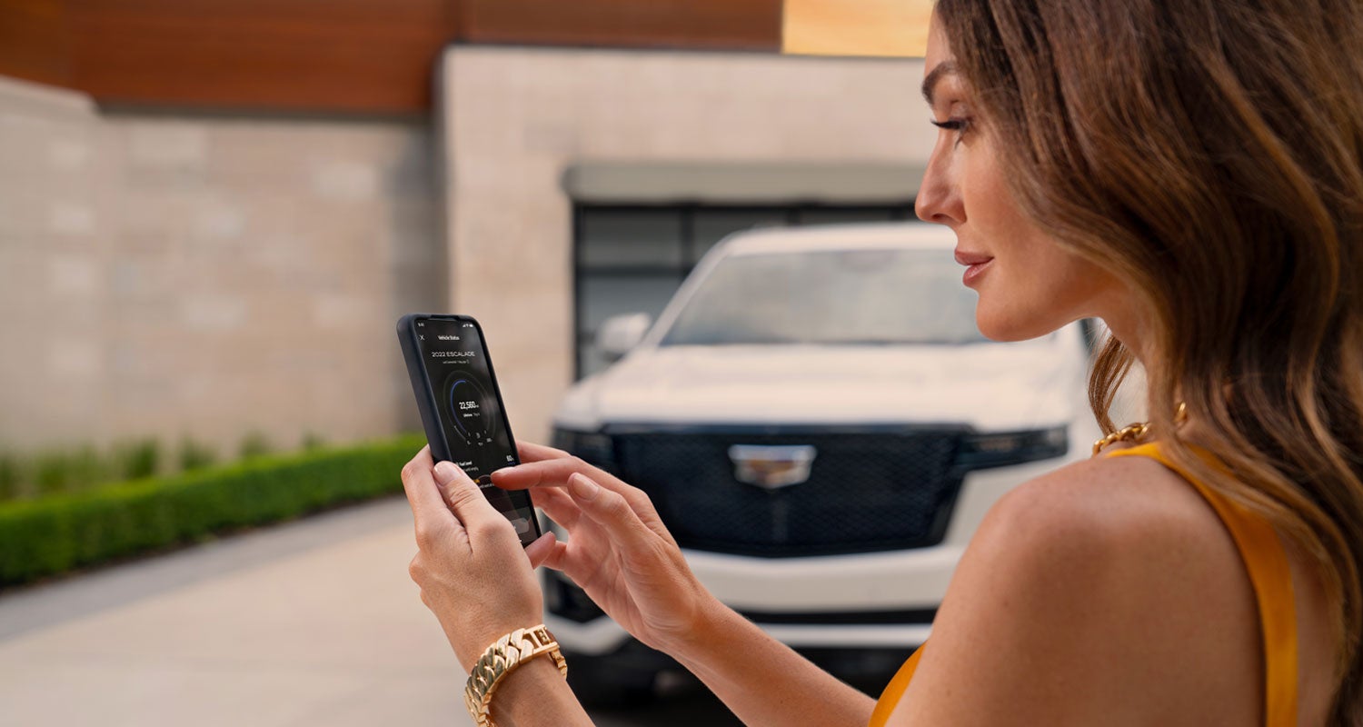 lady checking her mobile with a Cadillac vehicle background | Gerry Lane Cadillac in Baton Rouge LA